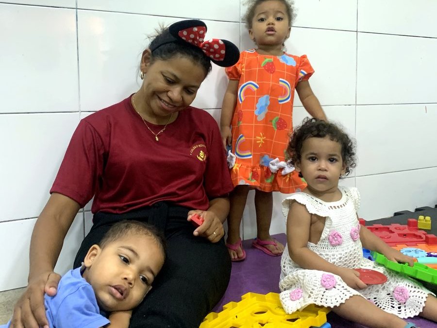 Professora do Colégio Nena Kids no chão brincando com bebês da turma do berçário