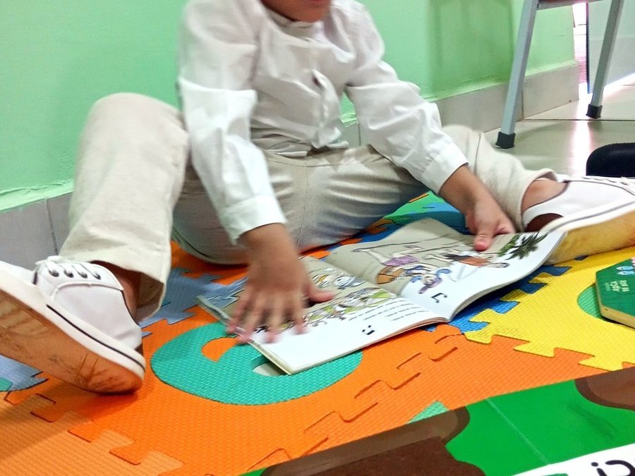 Criança do berçário do Colégio Nena Kids explorando um livro no tapete da sala