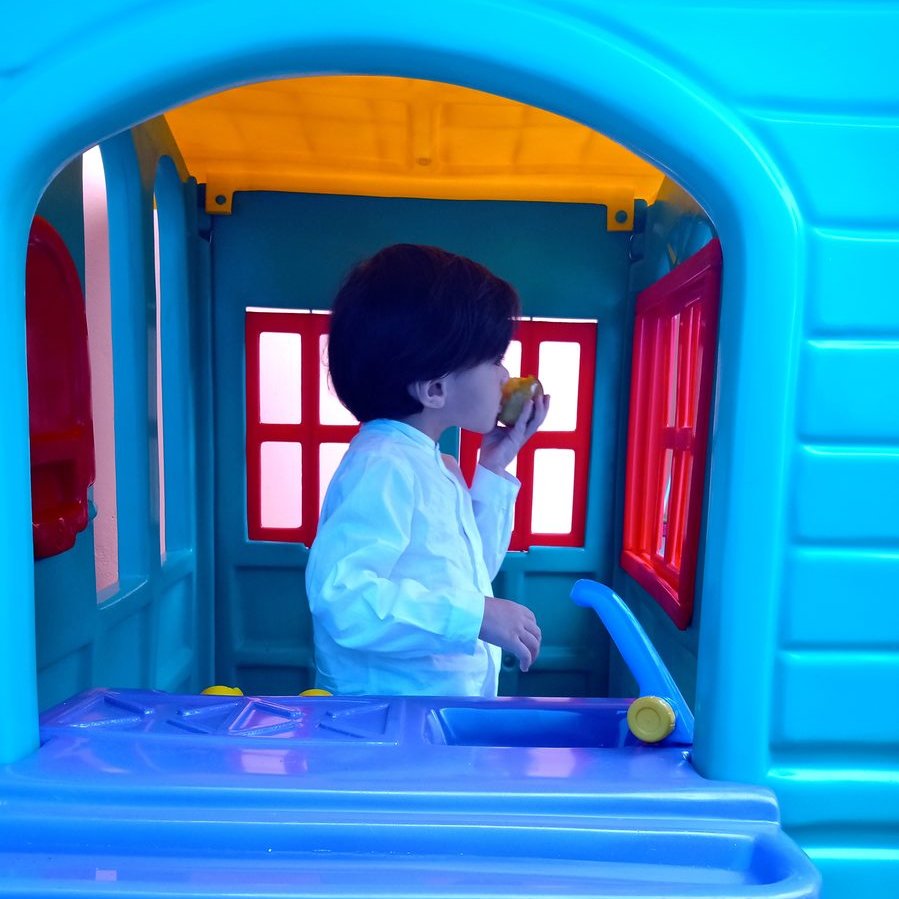 Criança brincando na casinha do espaço lúdico da escola